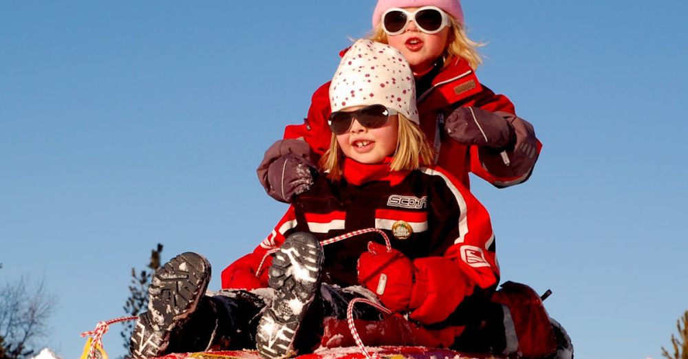 Sledding - Two children enjoying a fun sled ride down a snowy hill on a sunny winter day.