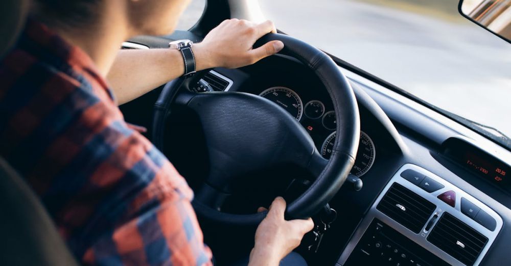 Drive - Close-up view of a man driving a modern car, showing dashboard and steering details.