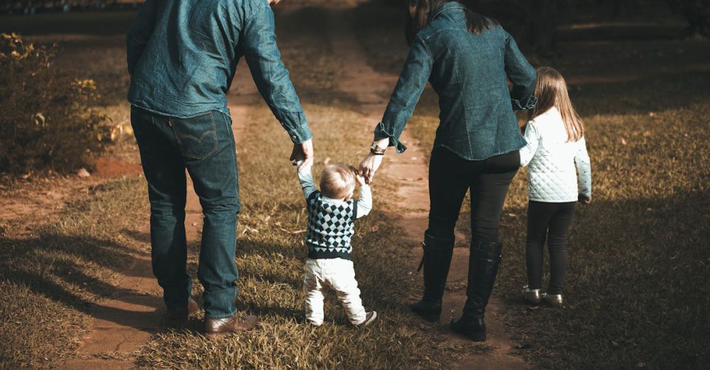 Family - A family of four walks hand in hand on a path, enjoying a sunny day outdoors.