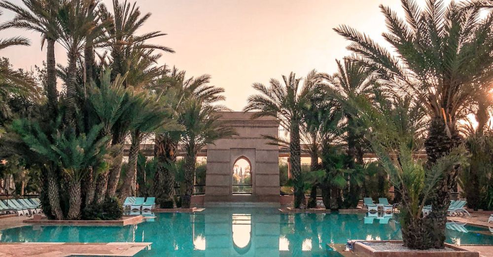 Luxury - Idyllic tropical resort pool with palm trees reflecting at sunset.