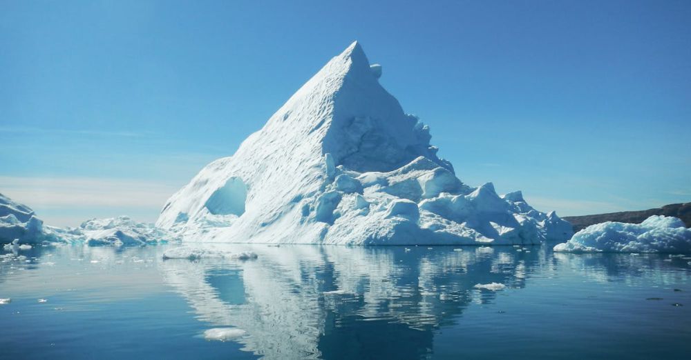 Arctic - Stunning view of a towering iceberg reflecting in the calm waters of Tiniteqilaaq, Greenland.