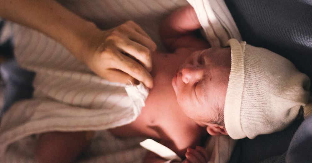 Newborn - A serene moment of a newborn baby swaddled in blankets with a tender touch of a parent's hand.