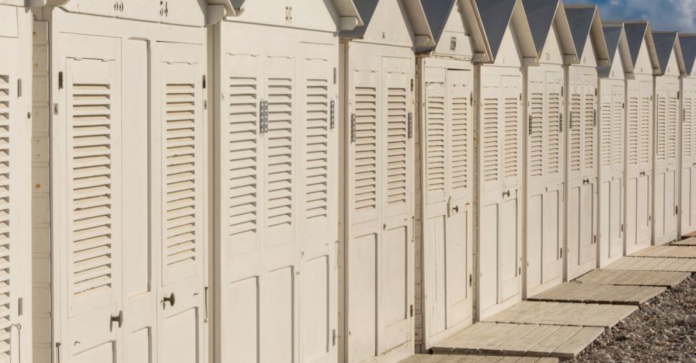 Cabins - A line of white beach huts under a clear blue sky, ideal for summer themes.