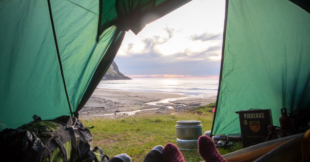 Camping - View from inside a tent overlooking a coastal sunset, capturing a relaxing camping experience.