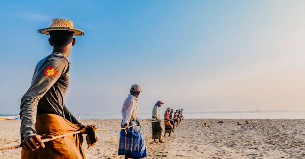 Fishing - A group of Sri Lankan fishermen pulling nets on a beautiful sandy beach during daylight.