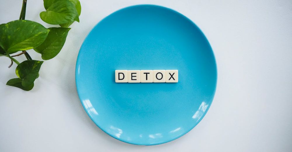 Detox - Minimalist concept of detox with letter tiles on a turquoise plate and green leaves.