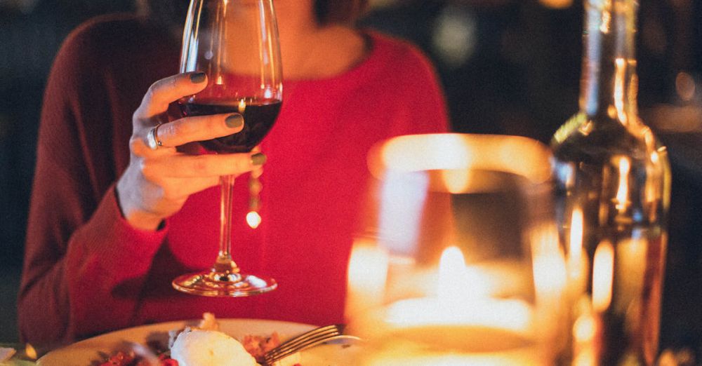 Dining - A woman enjoying red wine at a romantic candlelit dinner, perfect for celebrations.