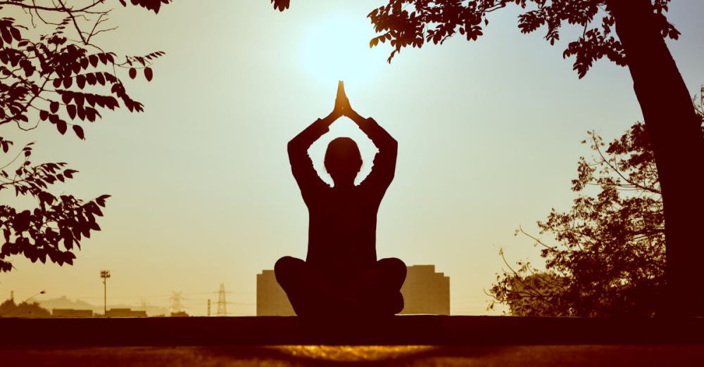 Yoga - Silhouette of a person practicing yoga outdoors during sunrise, creating a calming atmosphere.