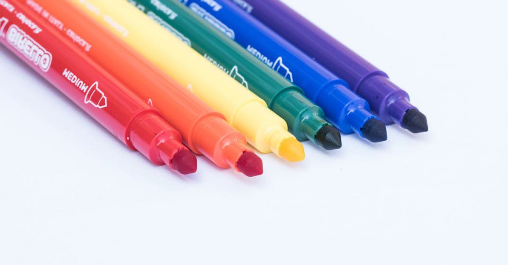 Markers - A close-up of six colorful markers arranged in a row, showcasing a spectrum of rainbow colors.