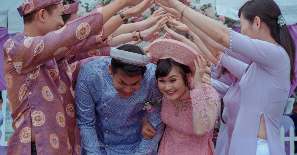 Wedding - Happy Vietnamese couple celebrates their wedding with friends in traditional attire outdoors.