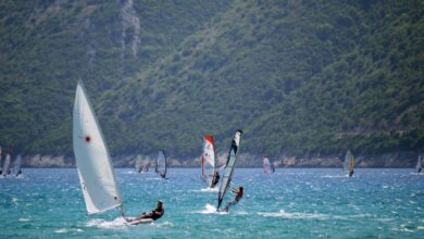 Windsurfing - Sailboats and windsurfers enjoy a sunny day on Vasiliki Bay, Greece with lush hills in the background.