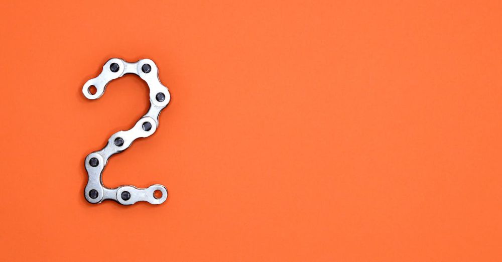 Gear - Metal chain forming the number 2 on a bright orange background, perfect for design projects.