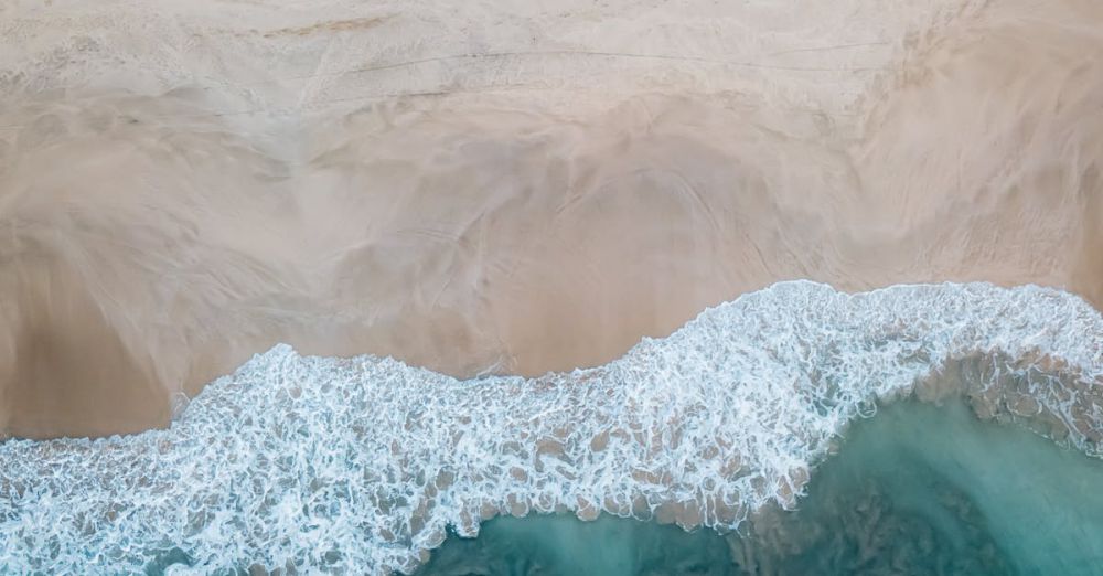 Coastal - A stunning aerial view showcasing a sandy beach meeting the turquoise ocean waves. Perfect for travel and nature themes.