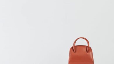 Luxury Handbags - Minimalist display of brown leather handbags on white pedestals with a clean background.