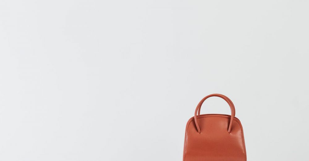 Luxury Handbags - Minimalist display of brown leather handbags on white pedestals with a clean background.