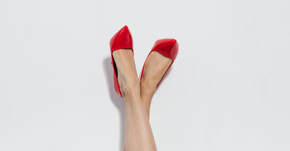 Designer Shoes - Close-up of legs wearing red stilettos against a white backdrop, showcasing modern footwear fashion.