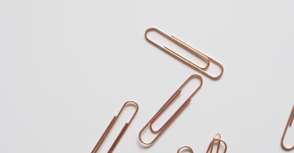 Clips - A collection of rose gold paper clips scattered on a white surface in a minimalist style.