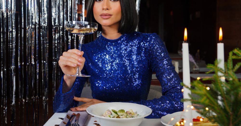 Luxury Experiences - A woman in a blue sequin dress toasts with champagne at a dinner party, with candles and festive decor.