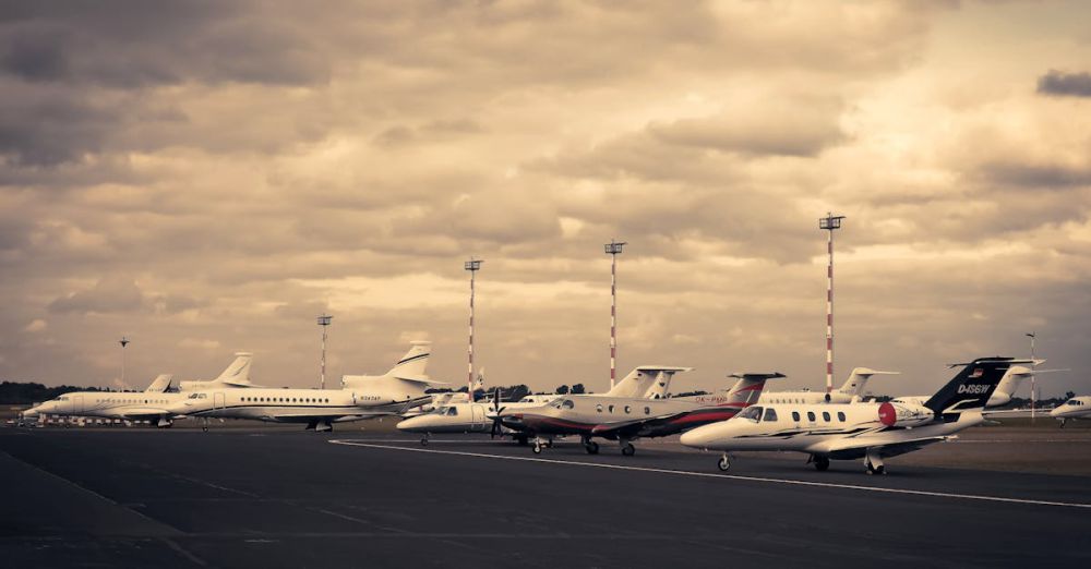 Private Jets - Line of private jets parked on the tarmac under a dramatic cloudy sky, showcasing aviation and travel.