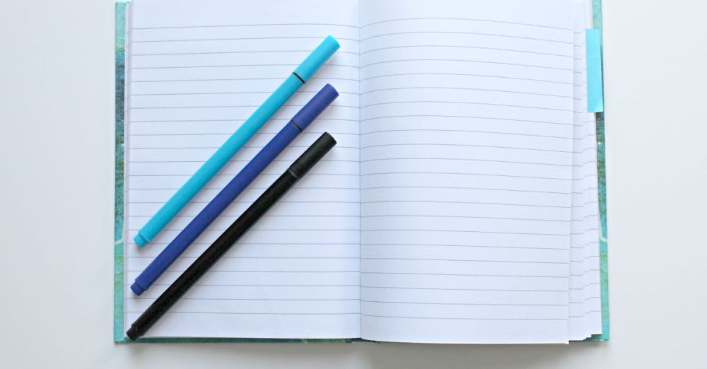 Pens - Open lined notebook with colorful pens on a white surface, perfect for note-taking and office tasks.