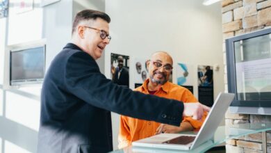 Sales - Two businessmen having a lively discussion in a modern office setting, pointing at a laptop screen.