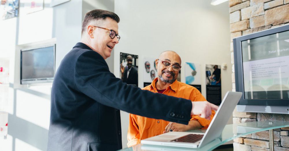 Sales - Two businessmen having a lively discussion in a modern office setting, pointing at a laptop screen.