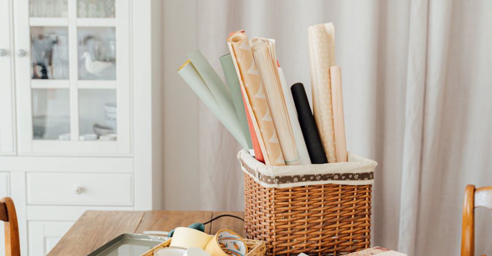 Wrapping Papers - Stylish gift wrapping scene with ribbons and baskets on a wooden table indoors.