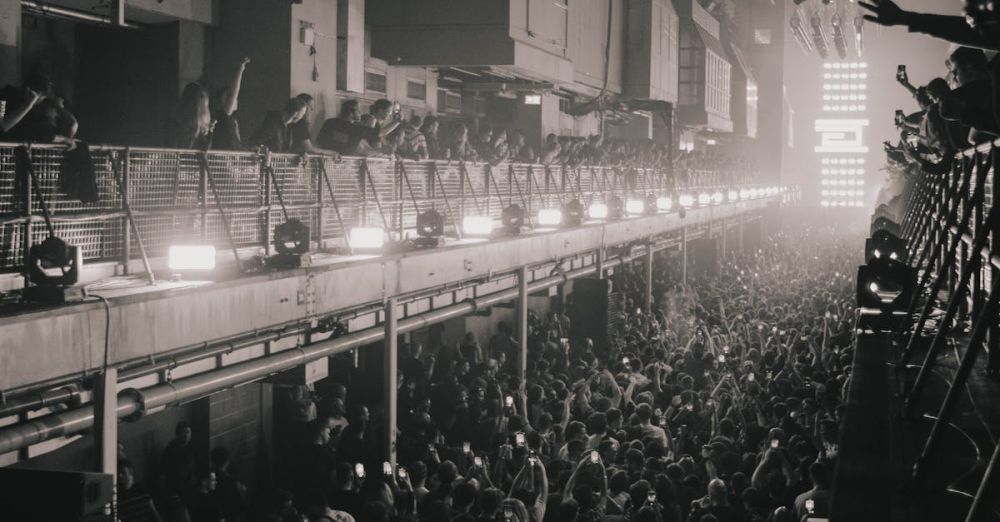 Warehouse Clubs - Black and white photo capturing a vibrant crowd in an industrial-style music venue.