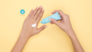 Beauty Products - Close-up of a woman's hands applying cream on a pastel yellow background. Ideal for beauty and skincare themes.