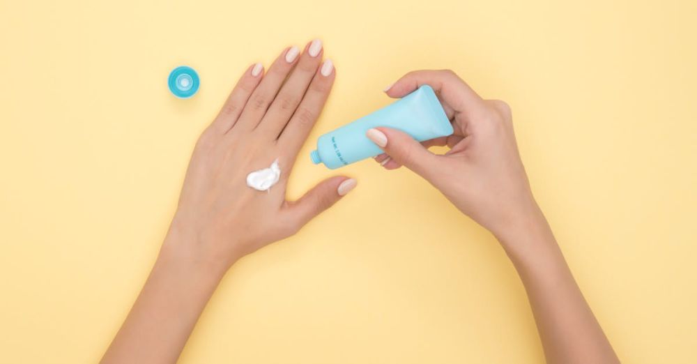 Beauty Products - Close-up of a woman's hands applying cream on a pastel yellow background. Ideal for beauty and skincare themes.