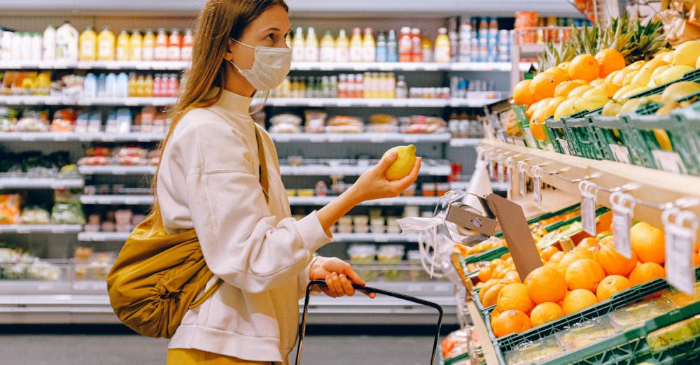 Grocery Shopping - A woman wearing a face mask shops for fruits in a supermarket during a pandemic.