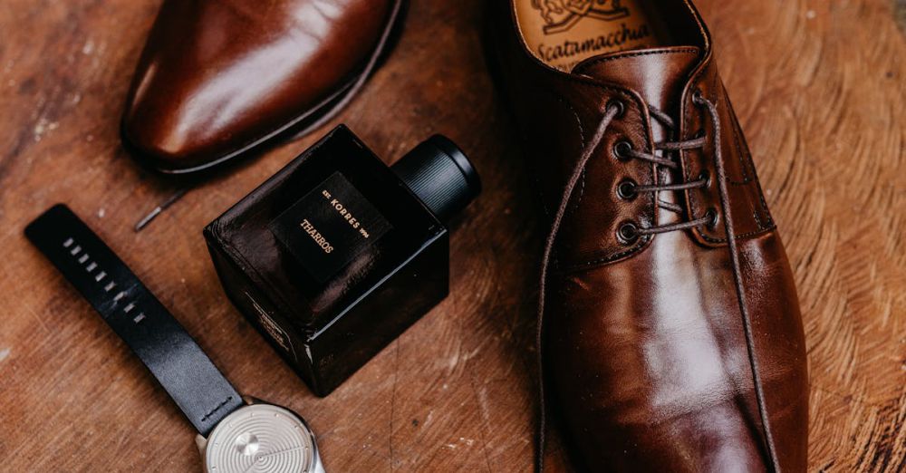 Luxury Items - Stylish brown dress shoes, watch, and perfume bottle on rustic wood.