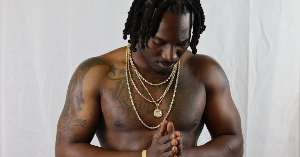 Jewelry - Athletic shirtless man with jewelry praying indoors. Moody portrait with tattoos.