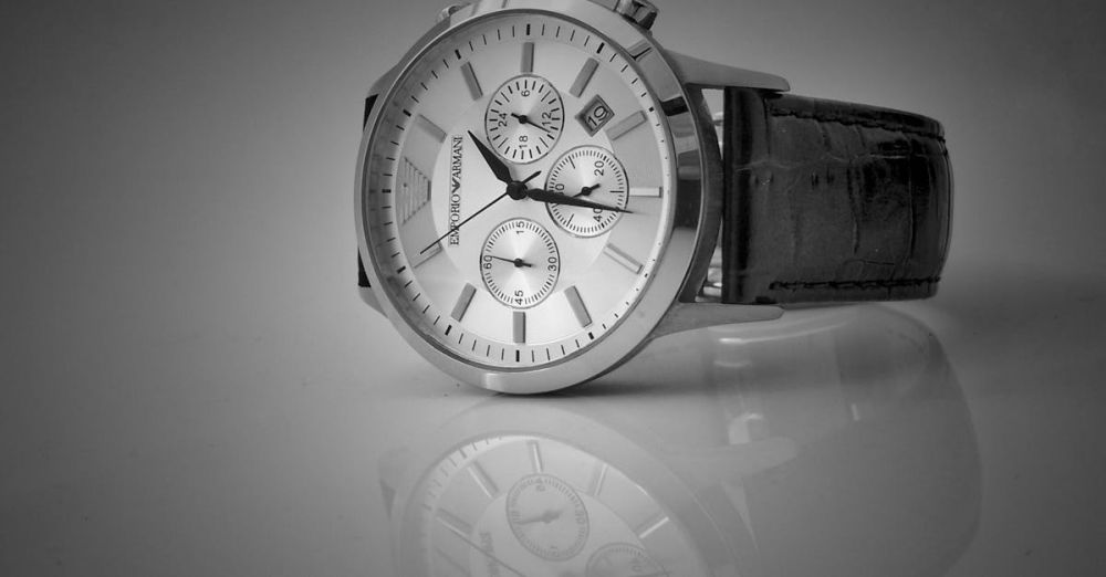 Watches - Elegant black and white close-up of a luxury wristwatch with a reflective stainless steel body and leather strap.