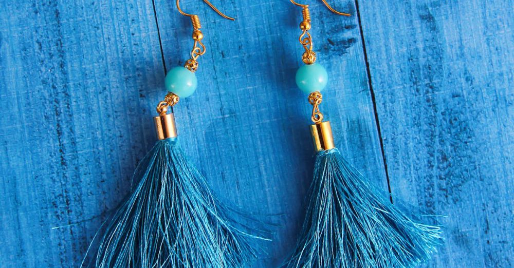 Earrings - Stylish blue tassel earrings with gold accents displayed on a wooden surface.