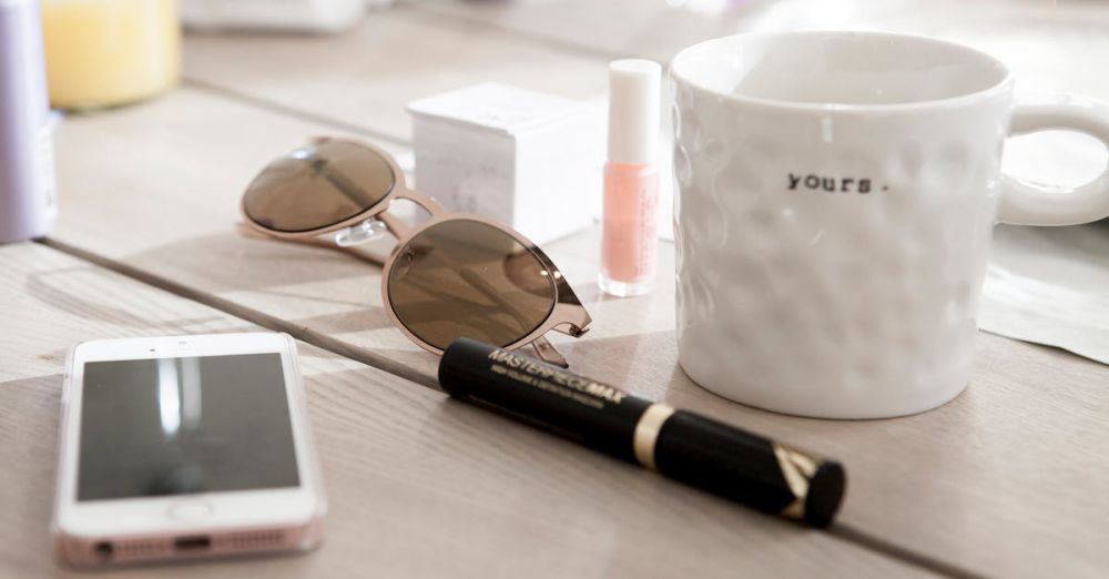 Accessories - Modern summer essentials like sunglasses and coffee mug on a wooden table. Cozy and stylish setting.