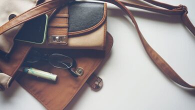 Wallets - Overhead view of leather bag with eyeglasses, wallet, and smartphone laid out.