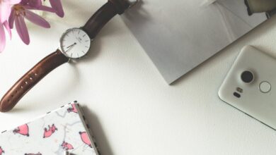 Accessories - Top view of a chic feminine workspace featuring coffee, flowers, and stationery.