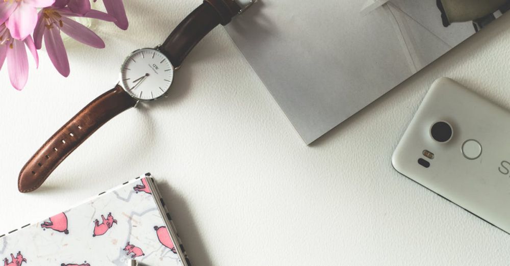 Accessories - Top view of a chic feminine workspace featuring coffee, flowers, and stationery.