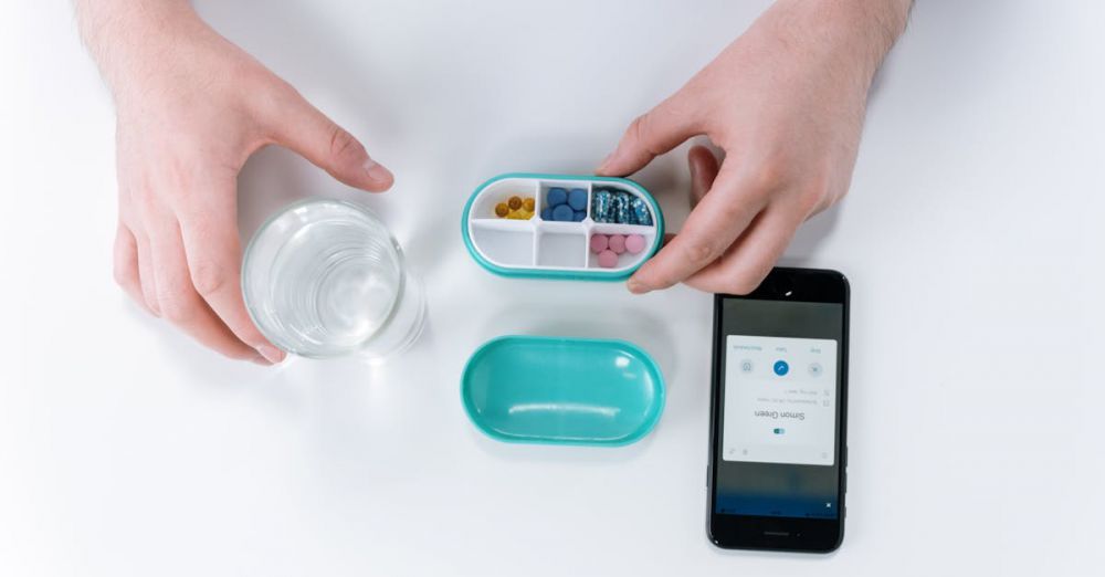 Calendar - Overhead view of hands using a smartphone app and pill organizer for medication management.