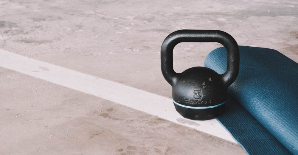 Yoga Mat - Kettlebell and blue yoga mat on a concrete floor in an indoor gym setting.