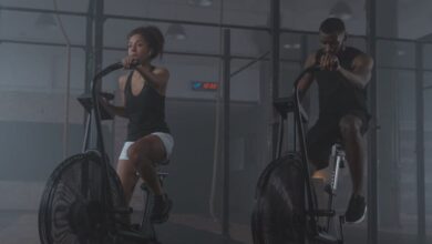 Exercise Bikes - A focused pair of athletes exercising on air bikes, showcasing endurance and fitness in a gym setting.