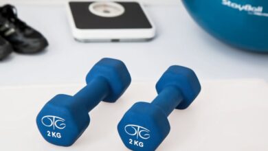 Exercise Equipment - Blue dumbbells placed on a white surface with fitness equipment in the background.