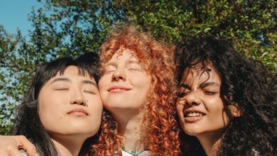 Weighted Vests - Three young women embracing outdoors, radiating friendship and happiness under a clear sky.