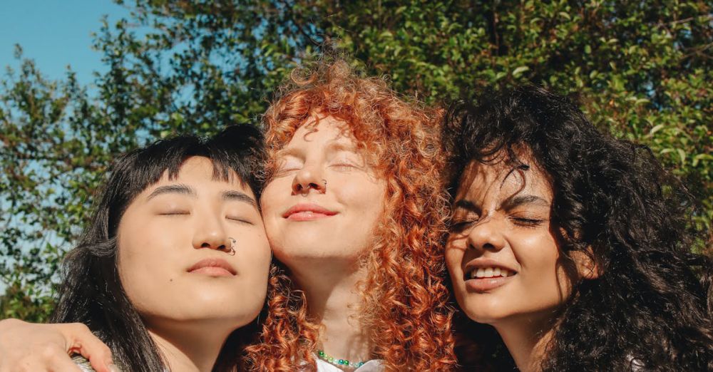 Weighted Vests - Three young women embracing outdoors, radiating friendship and happiness under a clear sky.