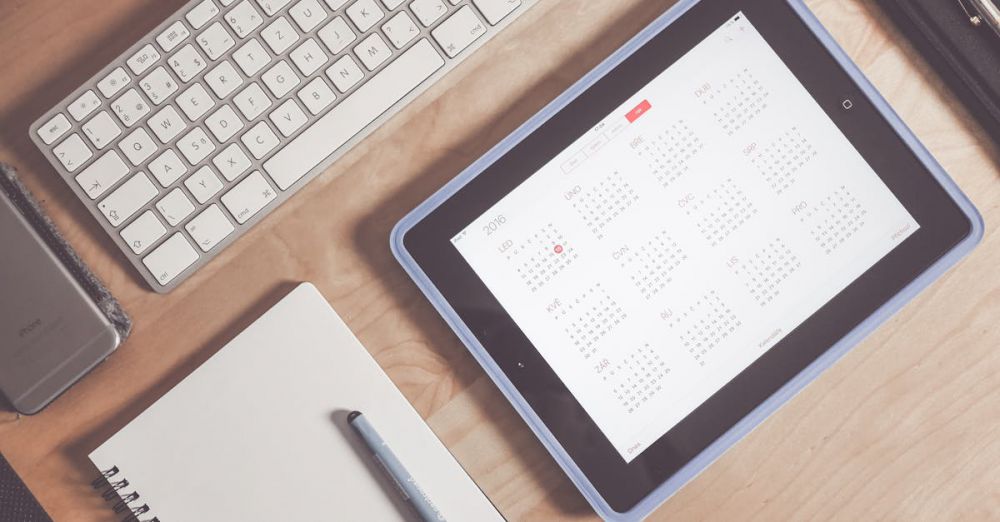 Calendar - A tidy desk setup featuring a tablet displaying a calendar, keyboard, and stationary items.