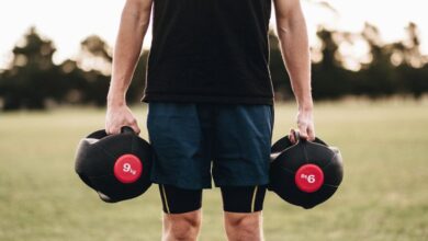 Medicine Balls - Man exercising outdoors with medicine balls in a park setting, promoting fitness and strength.