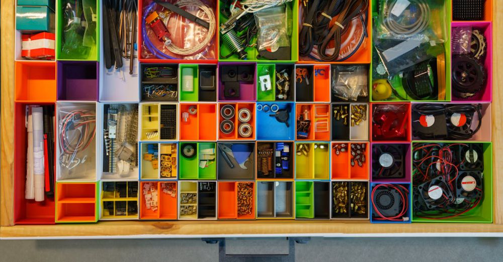 Stepper - Top view of a neatly organized drawer filled with colorful containers holding various tools and electronic parts.