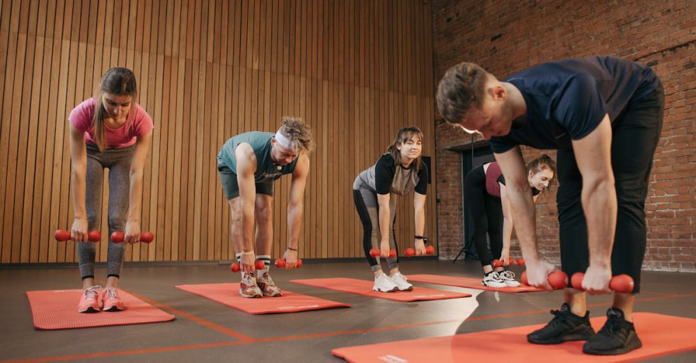 Workout Mats - Adults exercising in an indoor fitness class with dumbbells and yoga mats for healthy lifestyle.