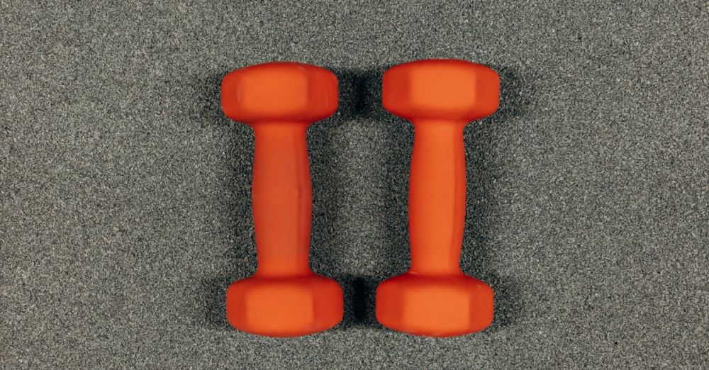 Strength Tools - A close-up image of orange dumbbells on a textured gray surface, ideal for fitness themes.